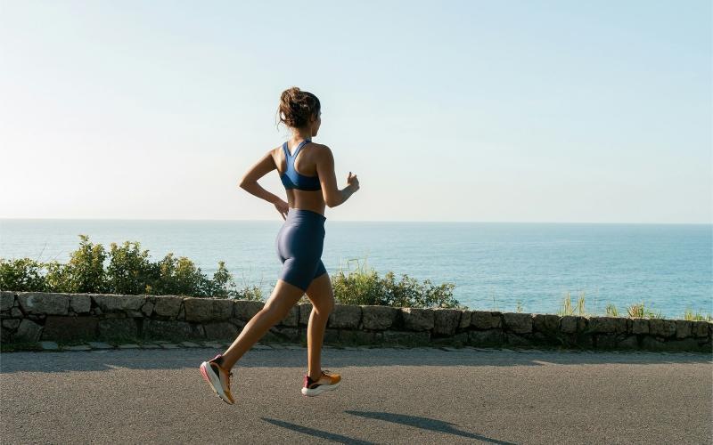 a woman running on a road by the water