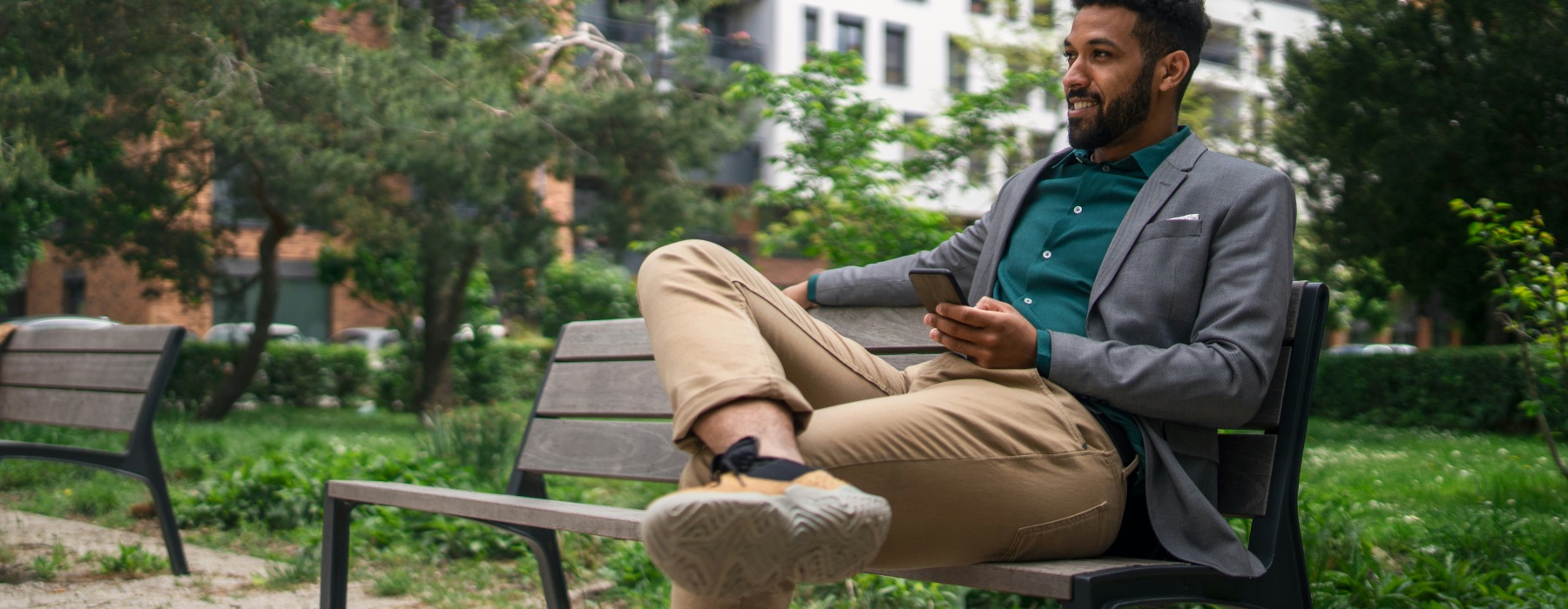 man holding a phone sitting on a bench